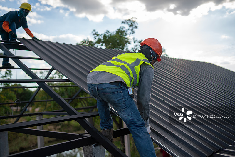 建筑工人在建筑工地上进行屋顶安装作业，工业环境，俯视视角，以提高搜索引擎排名图片素材