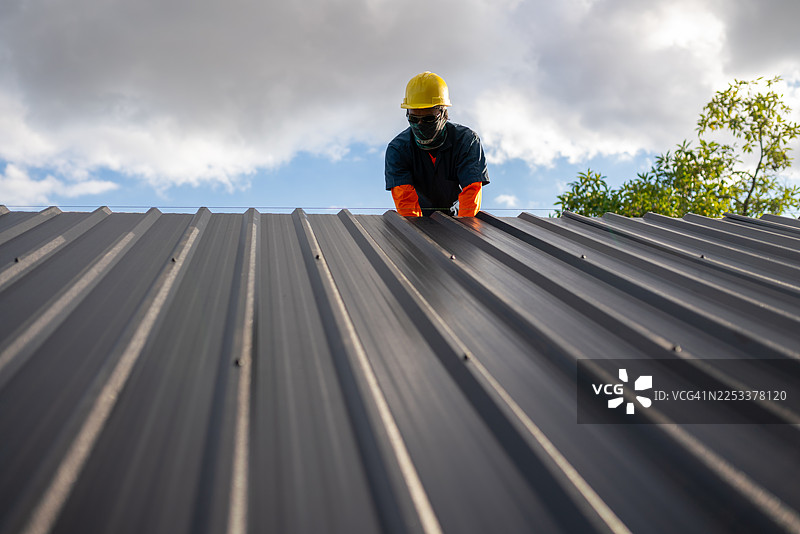 建筑工人在明亮的户外白天进行屋顶维修工作，特写镜头，注意安全规范。图片素材