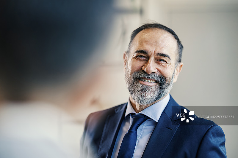 一位年长的成年商人面带微笑，看向镜头图片素材