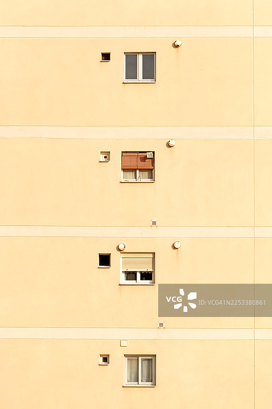 西班牙贝尼多姆市一栋黄褐色外墙的建筑，有四个不同公寓的窗户图片素材