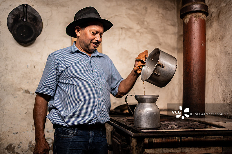 一位年长的男士在家里的柴火炉上加热咖啡图片素材