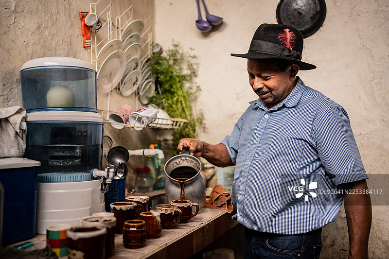 一位年长的男士在家中向杯子里倒咖啡图片素材