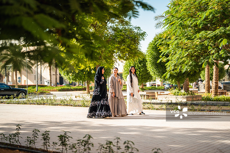 在利雅得大学校园里行走的快乐阿拉伯女性图片素材