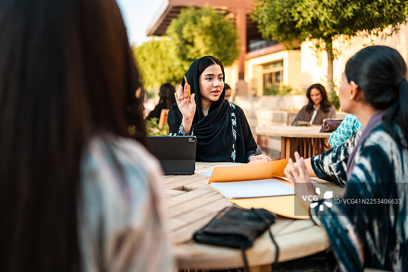年轻的中东女性在大学户外合作图片素材
