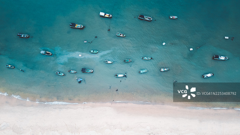 从空中俯瞰，众多渔船停泊在巴基斯坦一处沙滩附近，海水清澈碧绿。图片素材