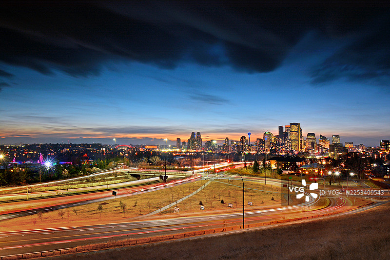 夜幕下，卡尔加里市的灯火辉煌的城市景观和繁忙的高速公路在高角度下尽收眼底，天空戏剧性十足图片素材