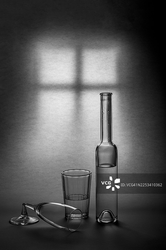 窗户阴影投射在墙上的静物，包含玻璃瓶、饮水杯和酒杯图片素材