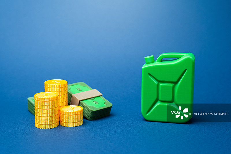 绿色燃料罐、成堆的硬币和成捆的钞票，在蓝色背景上代表燃料的成本图片素材