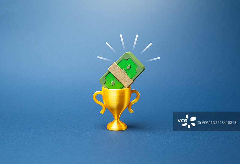 蓝色背景上堆叠的钞票和金色奖杯，象征着财务成功图片素材