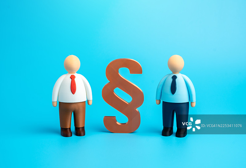 两个玩偶人物站在巨大的段落符号两侧，象征着法律事务或冲突解决图片素材