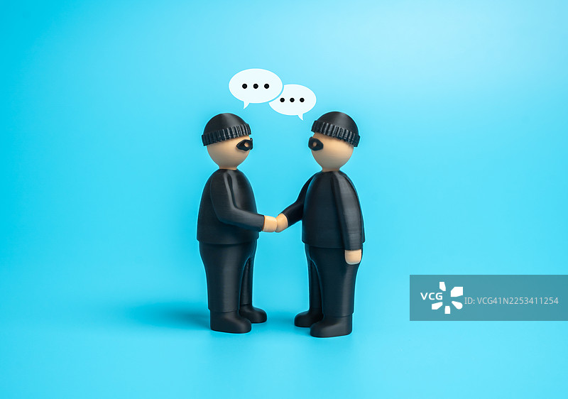 两个穿着劫匪服装的玩具人偶在蓝色背景上握手，头顶有对话气泡图片素材