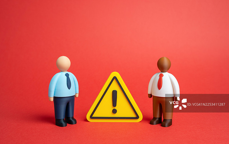 两个玩偶人站在黄色警示标志的两侧，背景为红色，象征着谨慎和潜在的问题图片素材