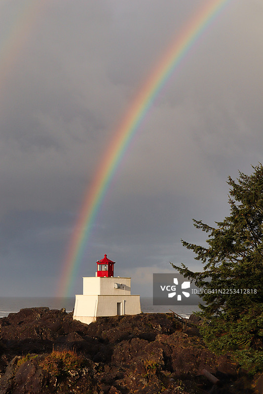 加拿大岩石海岸灯塔上的彩虹，背景为大海图片素材