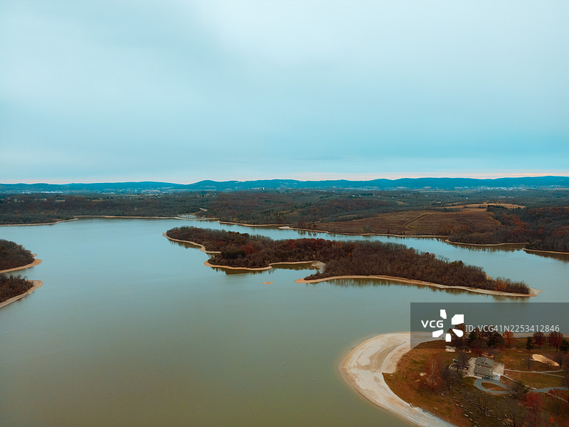 秋日林木环绕的山间湖泊，远处山峦叠嶂，天空辽阔，俯瞰视角图片素材
