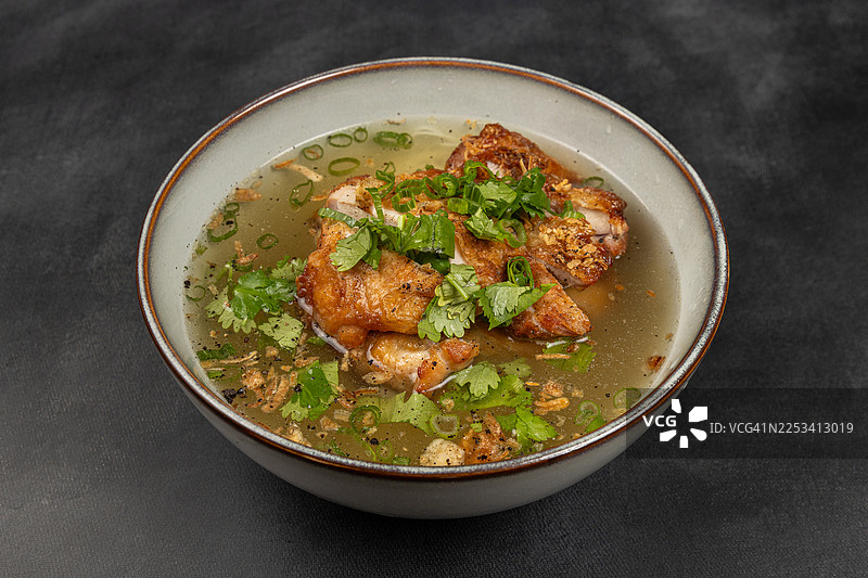 俯视视角，一碗美味的鸡汤配上新鲜香草，背景为深色图片素材