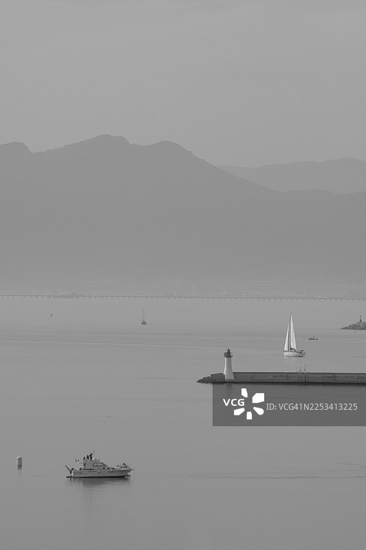 单色海景，包含山峦、灯塔和航行的船只图片素材