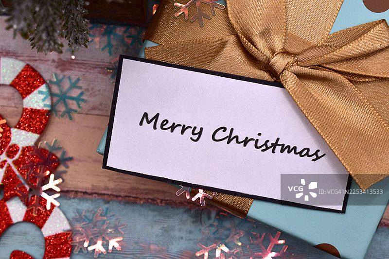 从高处看，一张乡村风格的木桌上摆放着圣诞装饰品和一份标有“圣诞快乐”的礼物图片素材