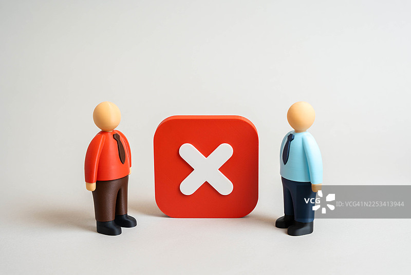 两个玩偶人站在一个大大的红色“X”符号两侧，象征着冲突或分歧图片素材