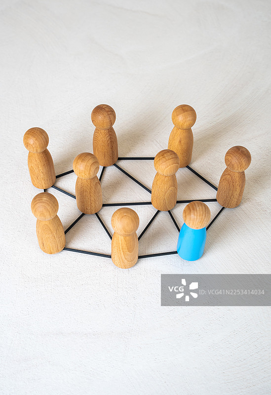 用线条连接的木制小人，其中一个蓝色小人脱颖而出，象征着团队合作和个性图片素材