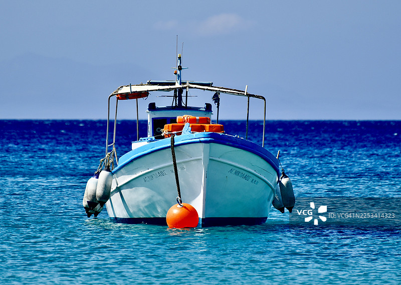 传统渔船在晴朗天空下的平静蓝海上漂浮图片素材