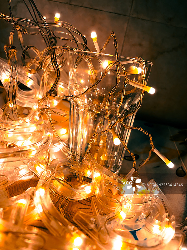暖色灯光装饰的圣诞串灯和透明玻璃制品营造出节日温馨的抽象背景图片素材