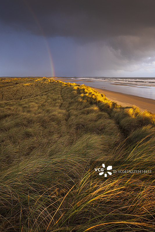英国，日落时分，暴风雨天空下的海景，沙丘上空出现彩虹，戏剧性的海岸景观图片素材