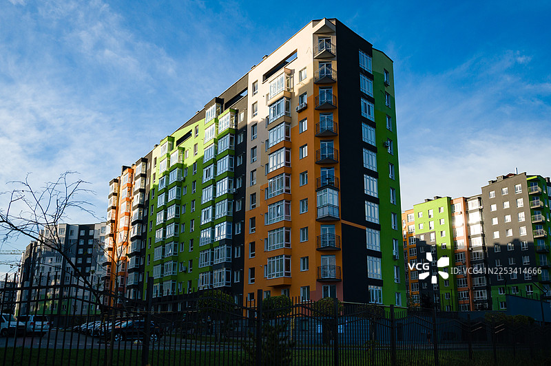 色彩鲜艳的现代住宅楼，拥有多彩的外墙，背景是晴朗的蓝天，展示着城市建筑和住房开发。图片素材
