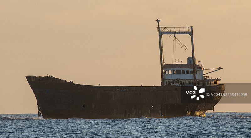 夕阳下海中生锈的沉船剪影，散发着神秘与历史的气息，塞浦路斯图片素材