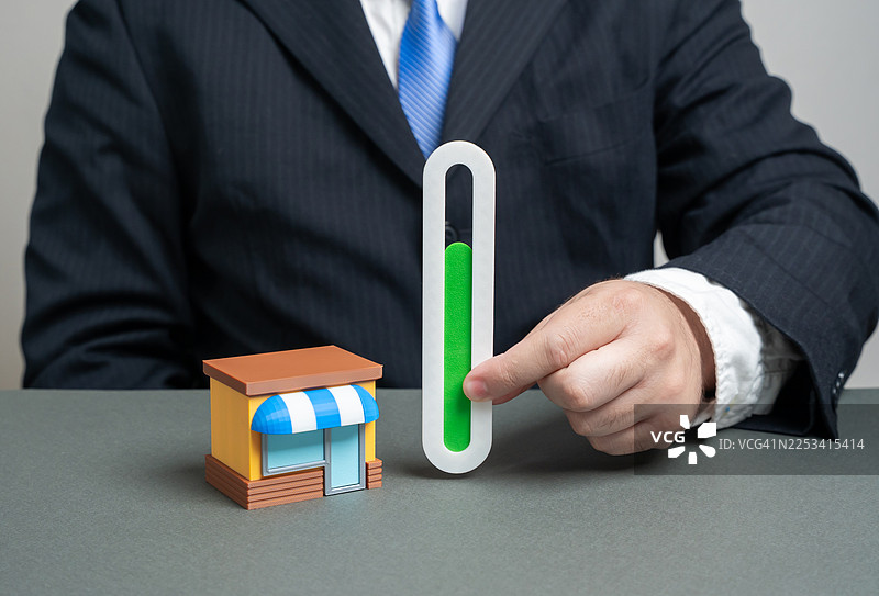商人的手正在调整迷你商店旁边的进度条，象征着业务的增长与发展图片素材