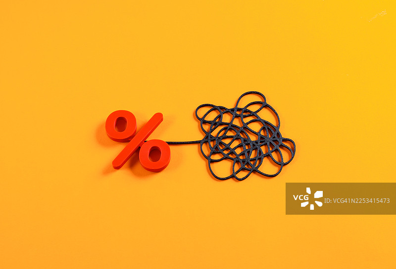 橙色背景上，百分号连接着一团缠绕的线结，象征复杂的金融问题或利率图片素材