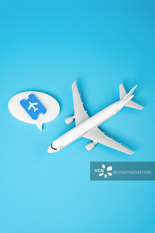 明亮的蓝天背景下，玩具飞机和机票图标，象征着旅行和预订图片素材