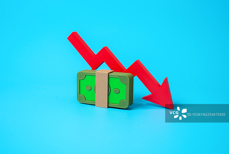 一叠玩具纸币和一个指向下方的红色箭头，象征着财政下滑或经济衰退，背景是鲜艳的蓝色图片素材
