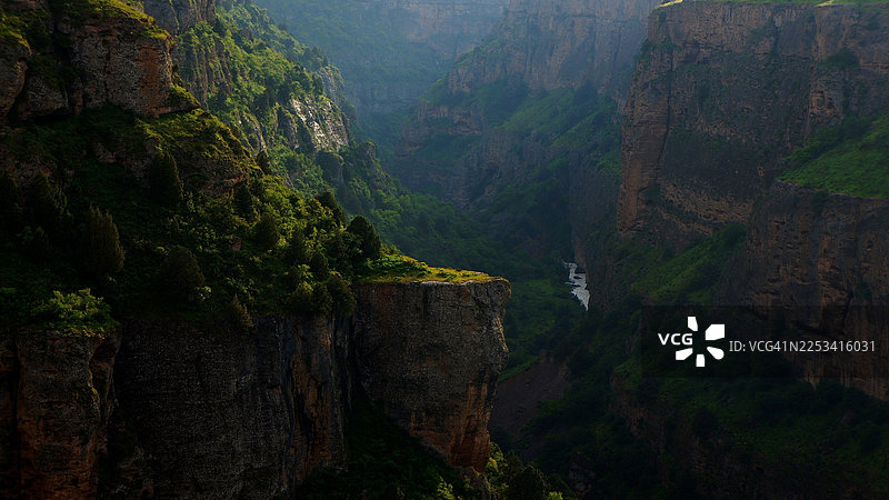 巴基斯坦，柔和光线下，戏剧般的峡谷风光，河流蜿蜒穿过郁郁葱葱的绿色山谷图片素材