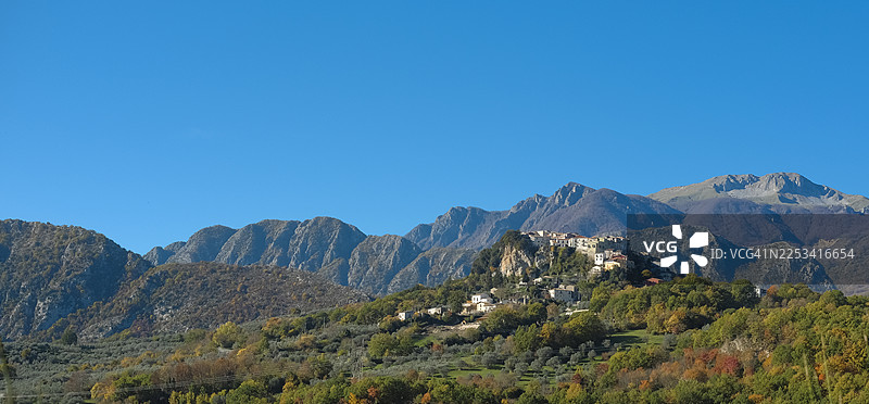 意大利风景：坐落在山坡上的迷人村庄，背景是群山和湛蓝的天空图片素材