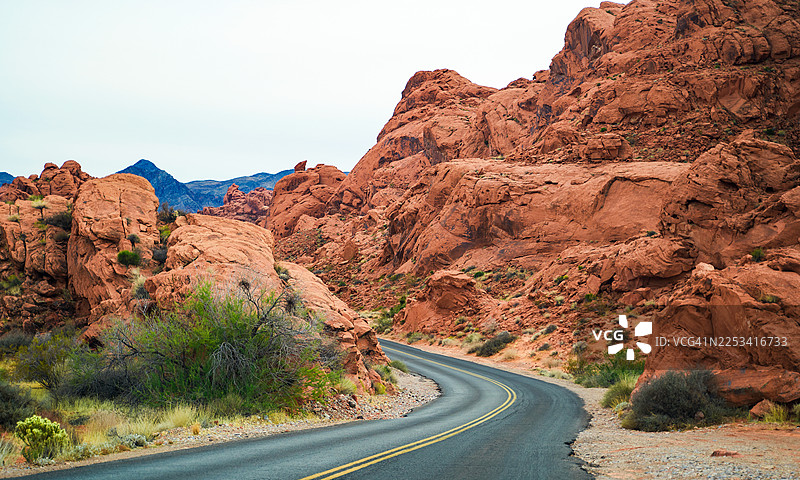 蜿蜒的道路穿过崎岖的沙漠峡谷，红色的岩石构造在晴朗的天空下，美国，内华达州，欧弗顿图片素材