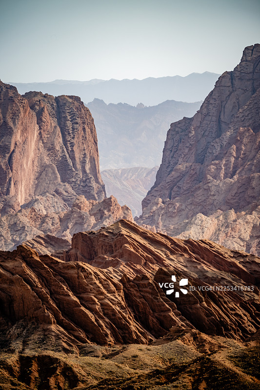 中国阿克苏地区库车市，晴朗天空下崎岖山脉与峡谷的壮丽景色，展示了地质构造和广阔的自然风光图片素材