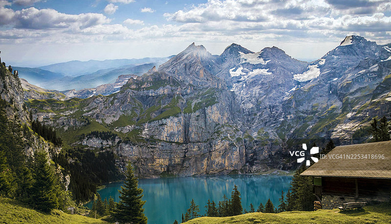 巴基斯坦，壮丽的山景，宁静的绿松石湖泊，以及云层下的乡村小屋图片素材