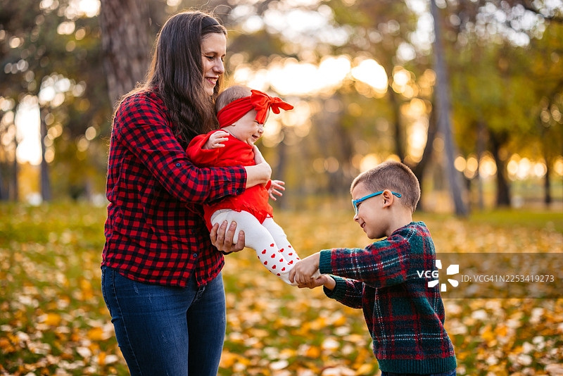 秋季在公园里，年轻的母亲和她学龄前儿子以及小女儿图片素材
