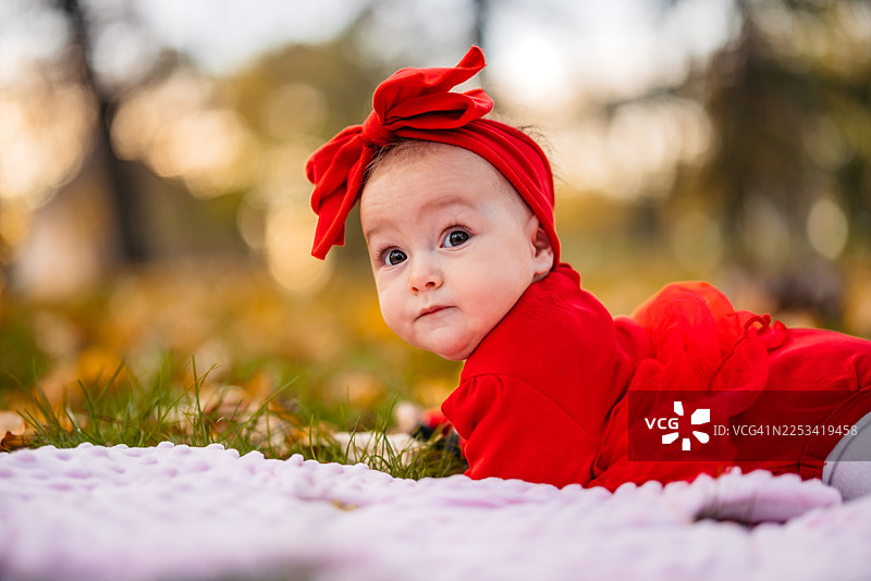 一个小女婴躺在公园的秋叶上图片素材
