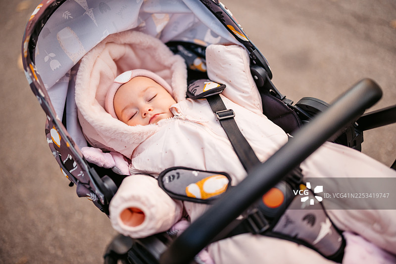 一个女婴在公共公园的婴儿车里睡觉图片素材
