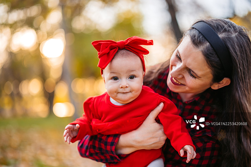 秋日里，年轻的母亲在公园里抱着她的女儿图片素材