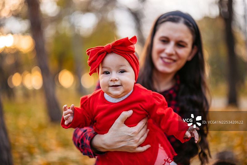 秋日里，年轻的母亲在公园里抱着她的小女儿图片素材