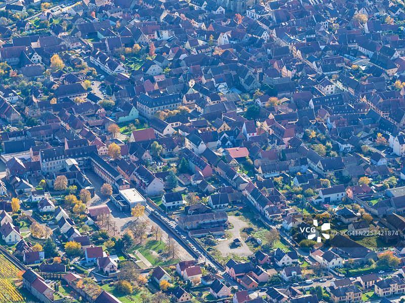 秋日树林环抱下的风景如画村庄的鸟瞰图，从上方展示了迷人的房屋和蜿蜒的街道图片素材