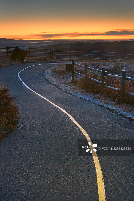 夕阳下蜿蜒的公路穿过风景如画的景色，天空色彩鲜艳，地面结霜，加拿大科克伦，格伦博牧场省立公园图片素材
