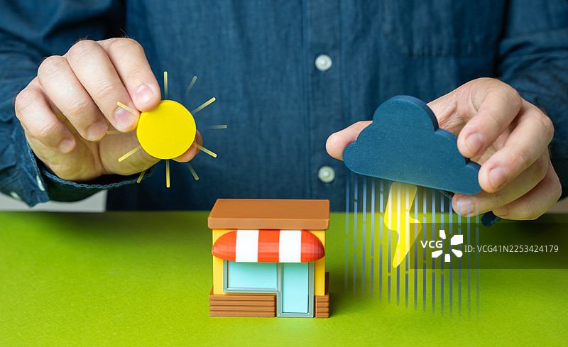一只手拿着太阳和风暴云的图标，放在一家迷你商店上方，象征着商业挑战与机遇图片素材