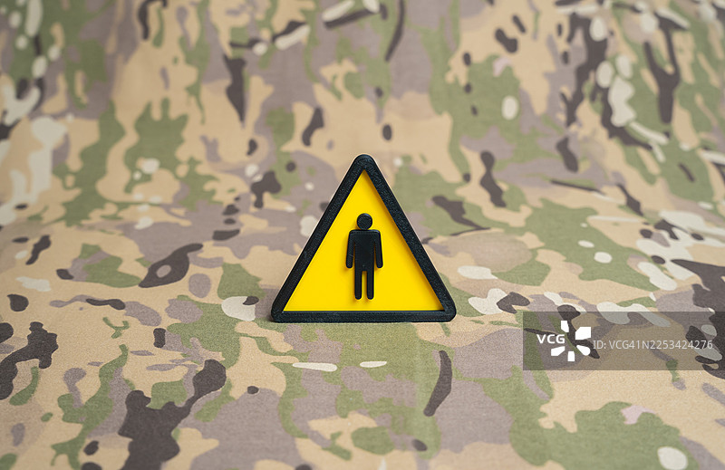 警告标志，带有伪装背景上的人物符号，象征军事或战术背景下的谨慎或危险图片素材