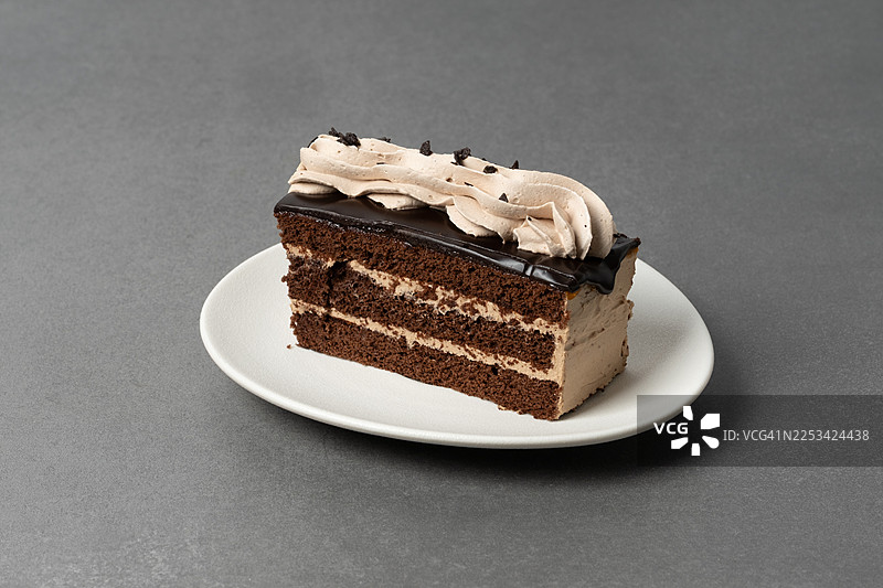 白盘子上的美味巧克力蛋糕切片，上面有奶油糖霜图片素材