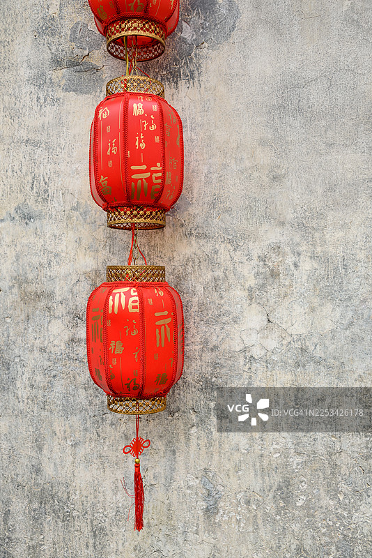 挂在灰色纹理墙上鲜红的中国灯笼特写，象征着好运和庆祝图片素材