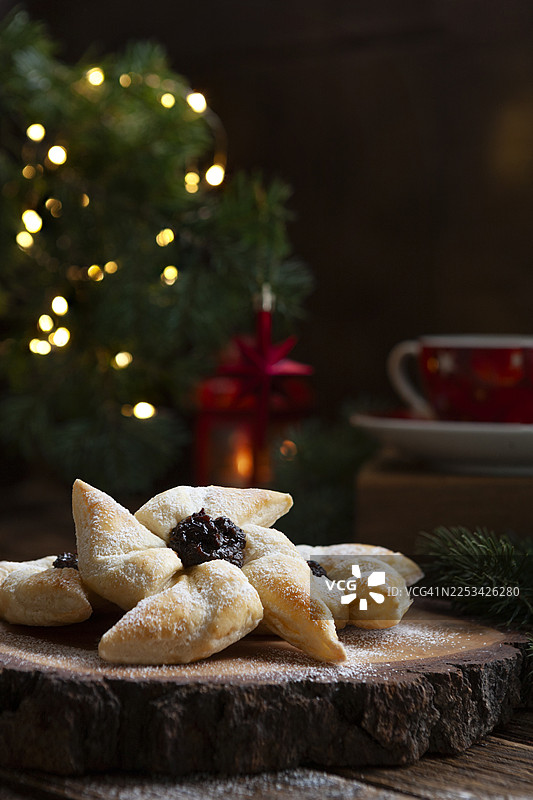 美味的圣诞饼干，带有水果馅和糖粉，摆放在乡村木板上，配有节日装饰图片素材