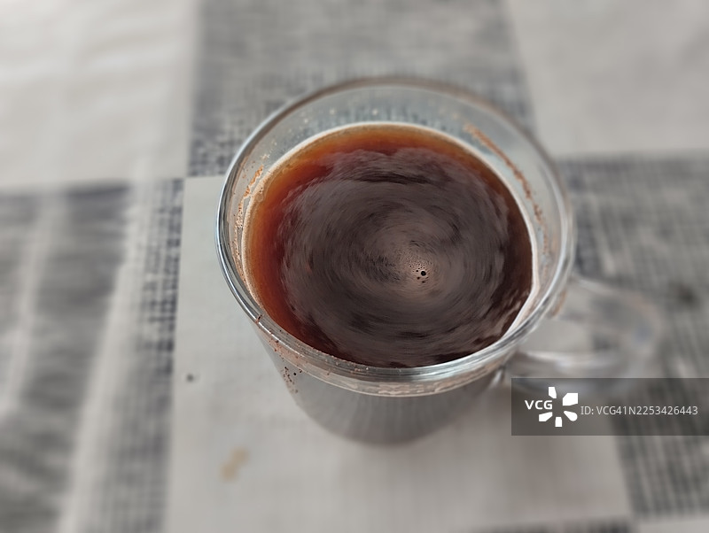 俯视视角，格子桌布上的一杯黑咖啡，表面有漩涡状图案图片素材